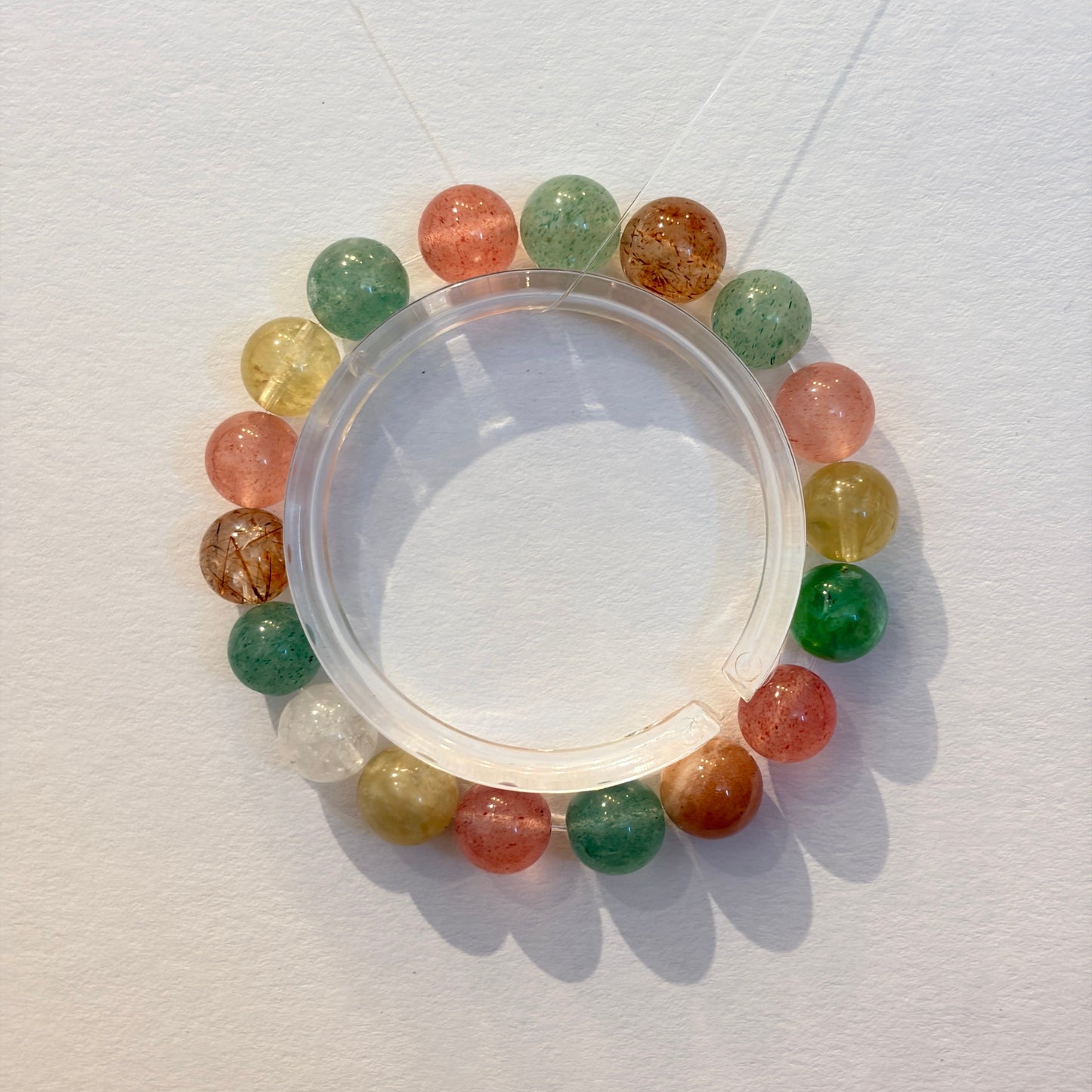 Handmade crystal bracelet with strawberry quartz, green aventurine, lemon citrine and clear quartz beads arranged on an elastic strand